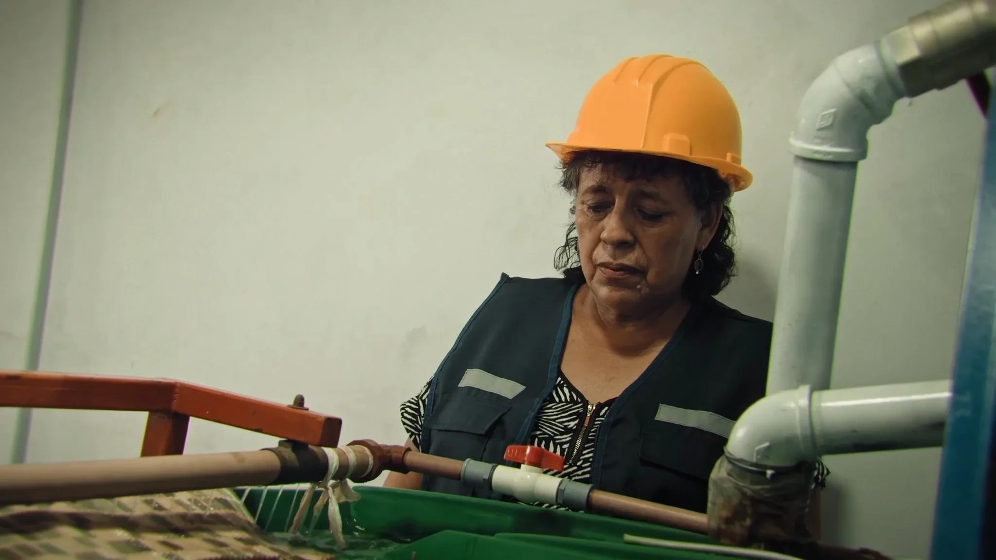 Una minera con casco amarillo mira a cámara