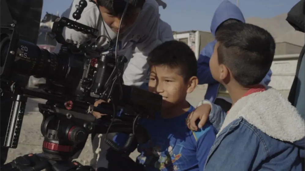 Niños del pueblo miran el monitor de la cámara