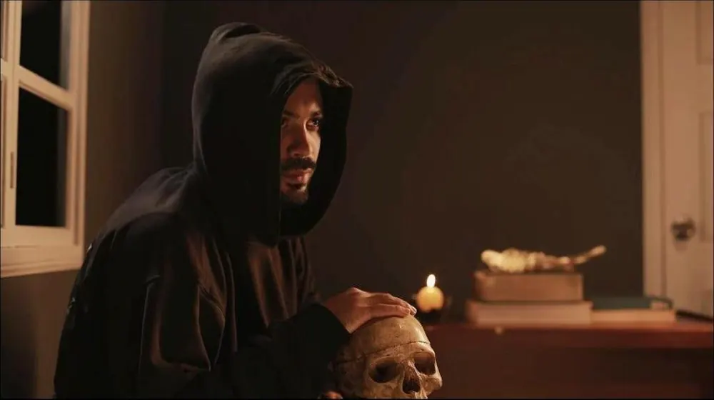 Jose Adrianzen actuando, encapuchado y con una calavera y una vela